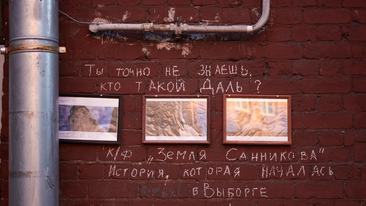 Graffiti on a brick wall with russian text and framed images.
